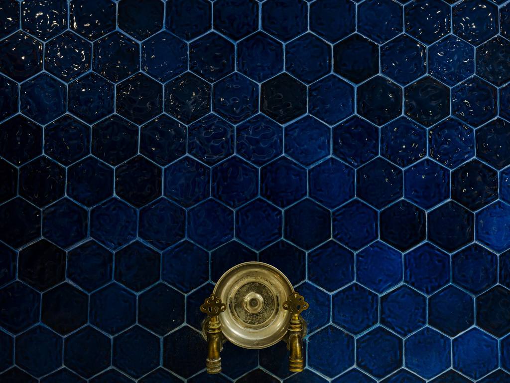 Brass tap against blue hexagonal tiles