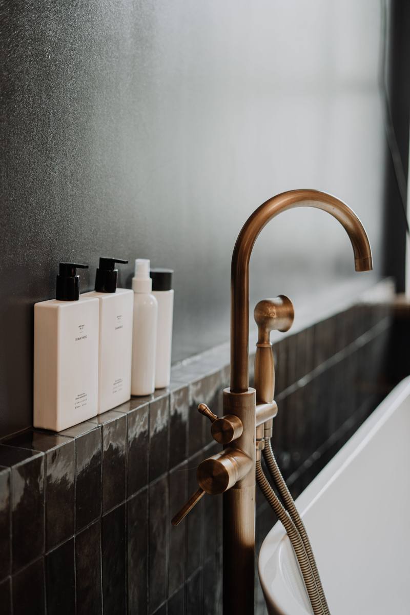 Gold tap beside bathroom toiletry bottles